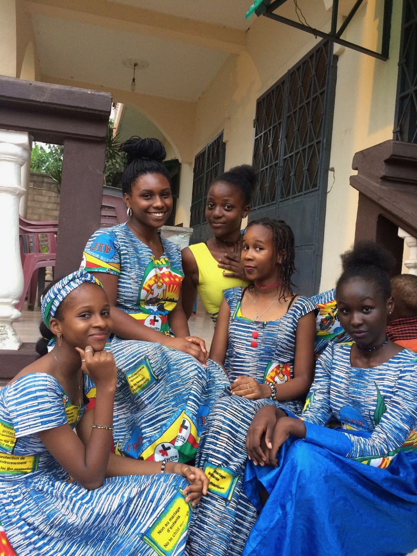 A student and her friends sit together wearing Cameroonian fabric dresses