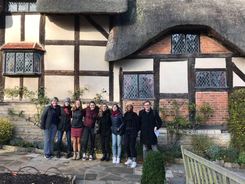 Students in front of a thatched roof house