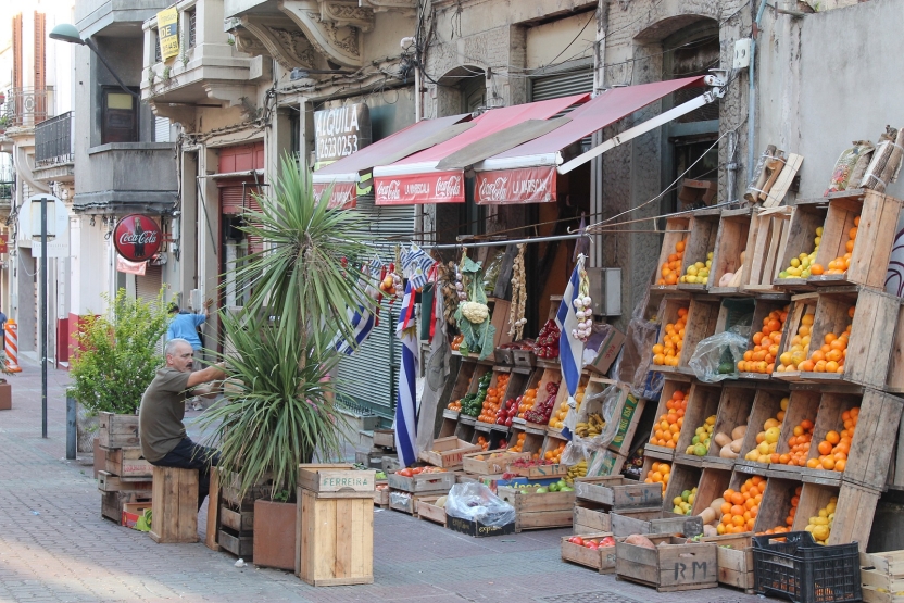 a man sits in front of a store with fruit in boxes in front