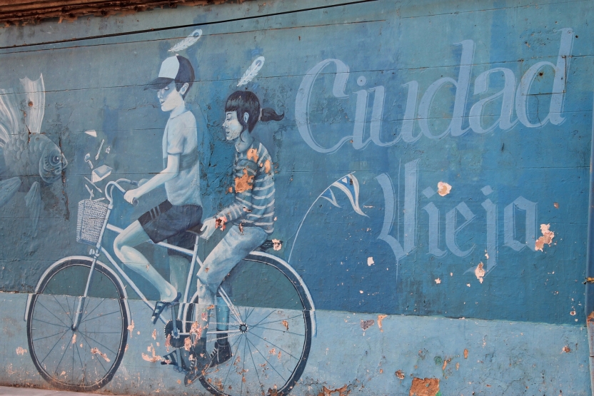 a mural of a boy and girl on a bicycle, with the text "Ciudad Vieja"