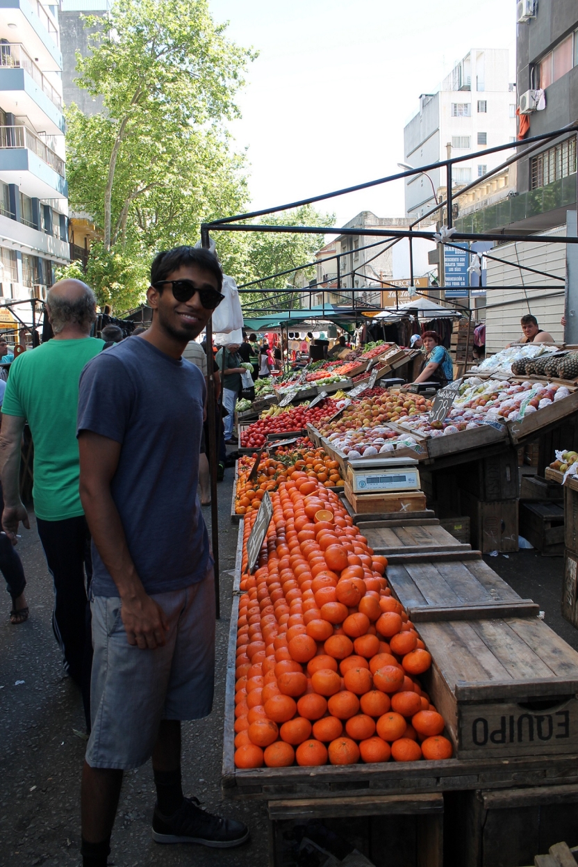 A student at a market with a stand full of oranges