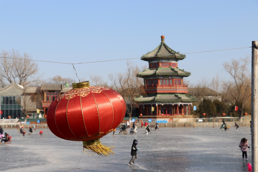 An ice rink with a lantern in the foreground and a building in the background
