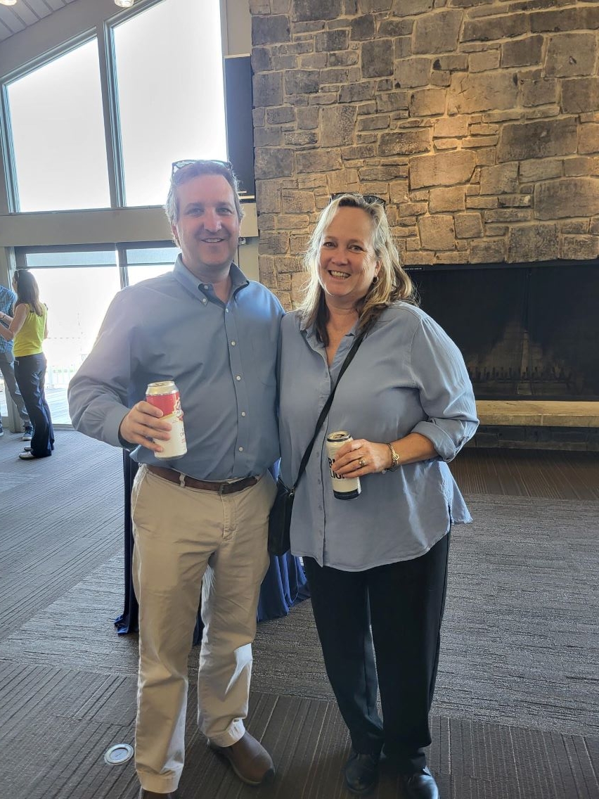 Colleagues standing, smiling, holding drinks