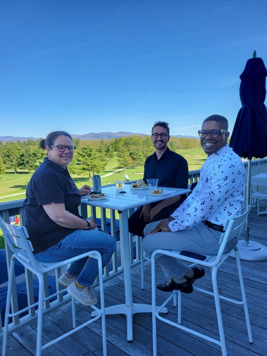 Three Colleagues sitting together smiling on the porch overlooking the golf course.