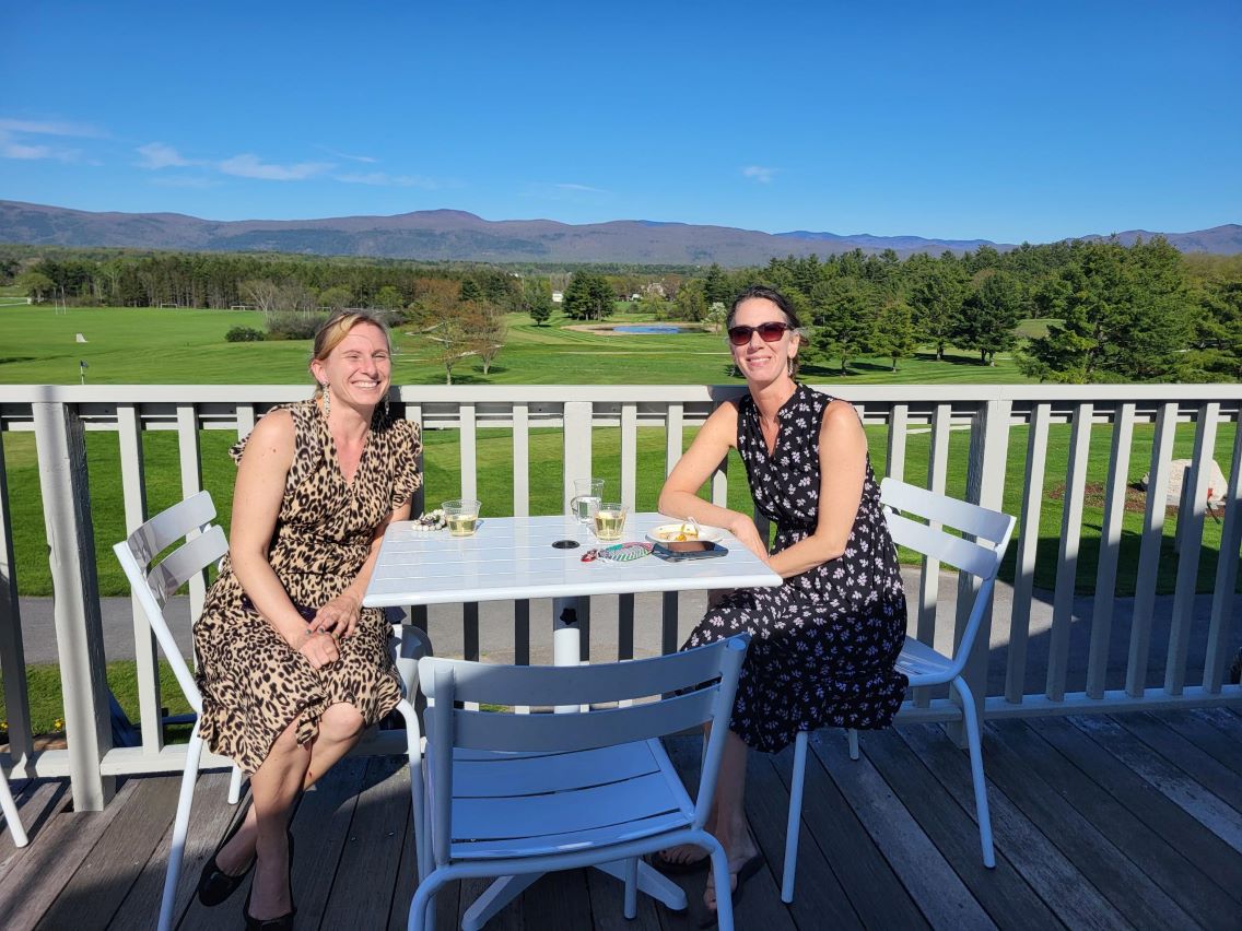 Two Colleagues sitting smiling enjoying the sun and drinks