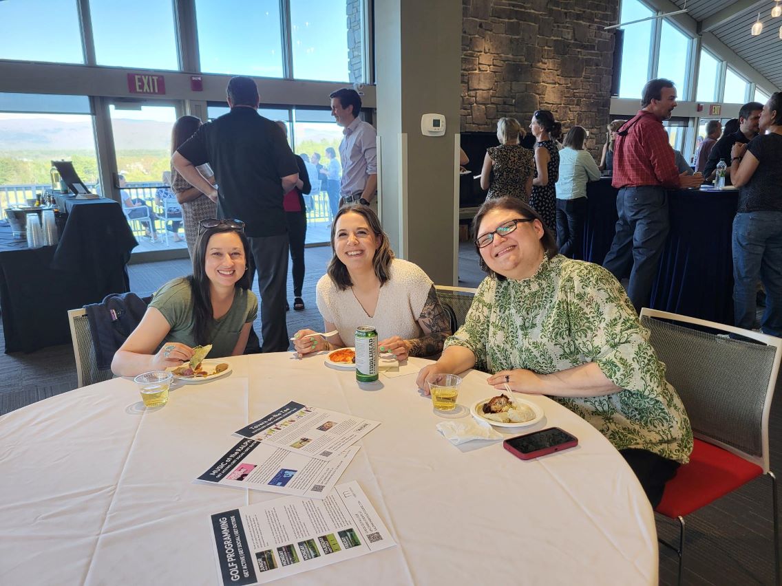 Three colleagues sitting smiling enjoying appetizers