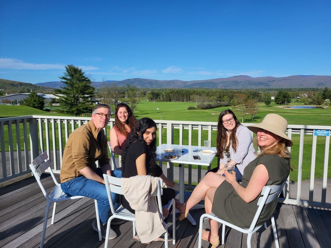 Five colleagues sitting together enjoying the sun overlooking the golf course and mountains