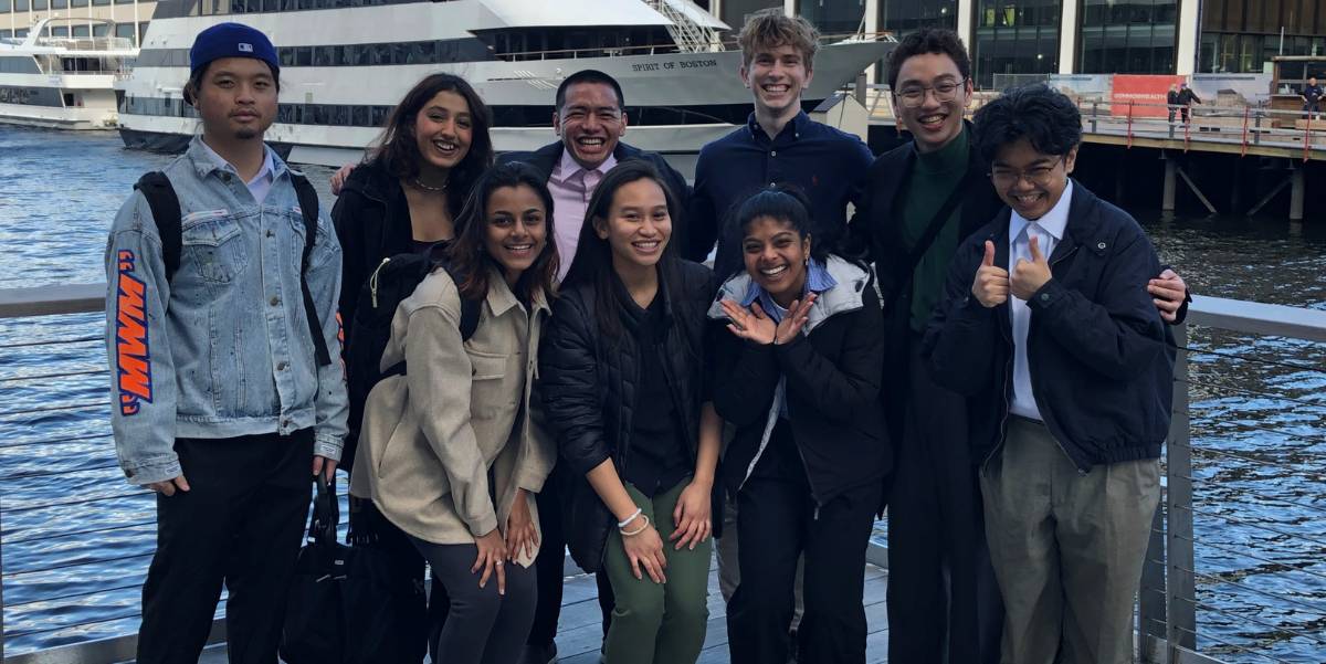 A group of students are posing at eh Boston Pier.
