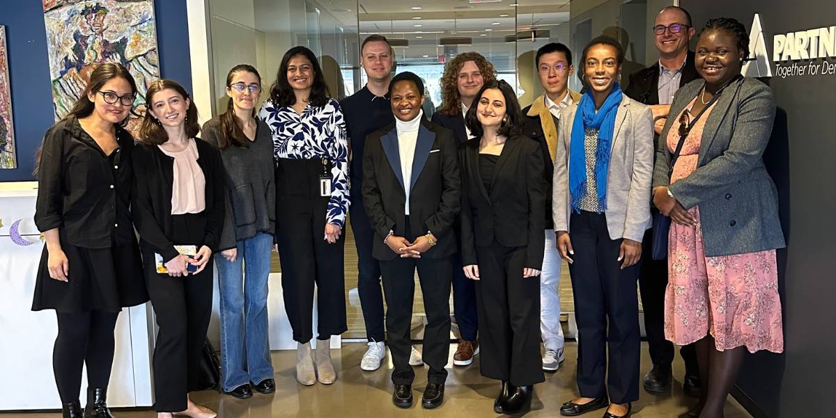 A group of students pose with alumni in a lobby.