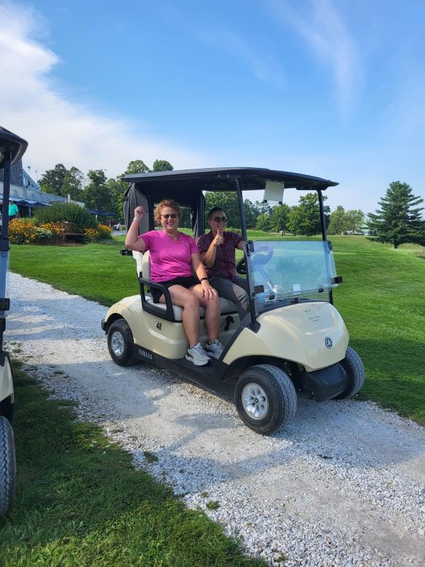 Two colleagues driving golf cart