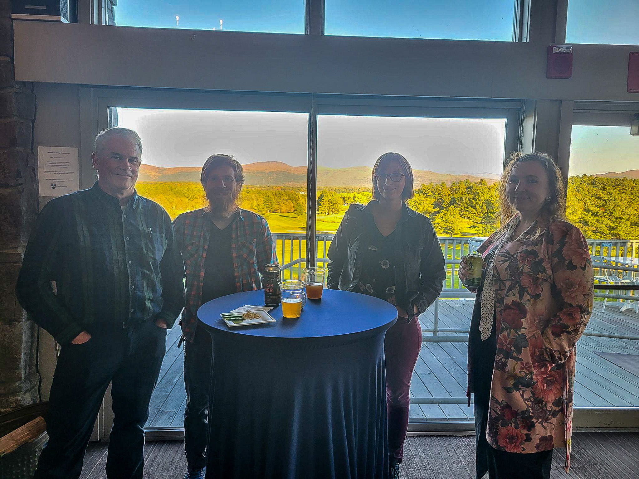 colleagues standing together smiling in front of big windows