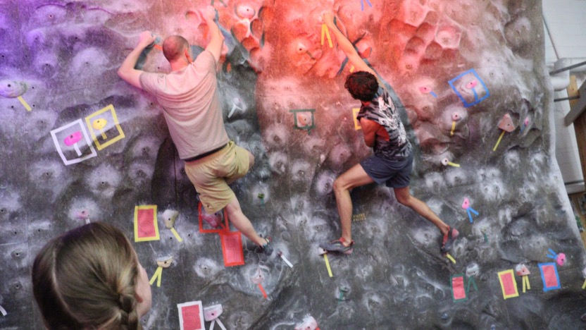 a student observing two climbers on the wall.