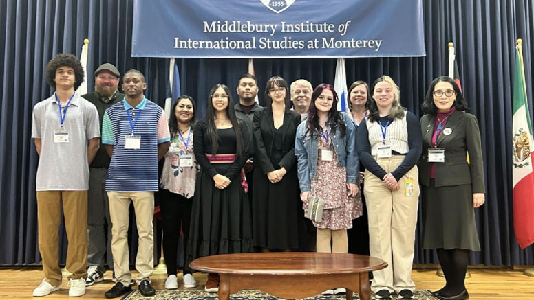 People stand for a photo in front of a banner for the Middlebury Institute.