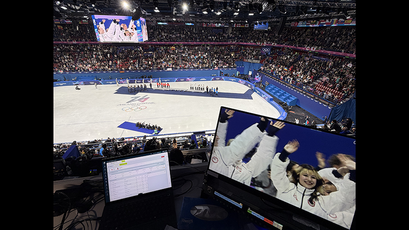 A computer screen in the NBC booth in the high seats above the ice area shows celebrating Team USA skaters