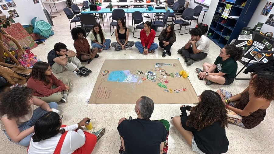 A group of students sitting around a piece of brown paper co-creating a conceptual body map of Puerto Rico