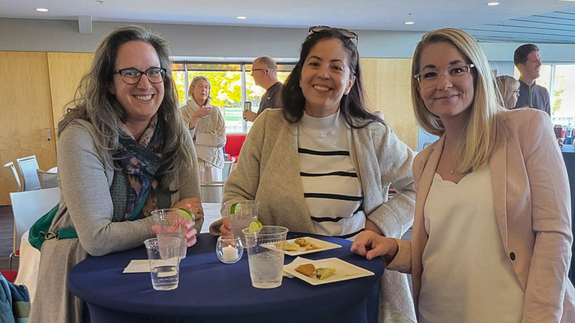 three women smiling at employee fall social event