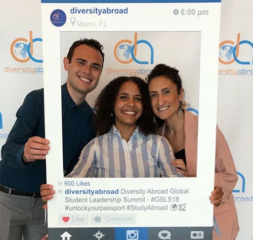 Three students pose for photo inside life-sized Instagram frame.