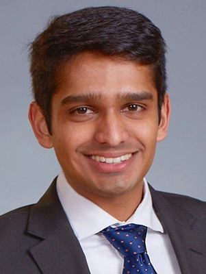 Jigar Bhakta in a dark suit, white shirt, and dark blue tie