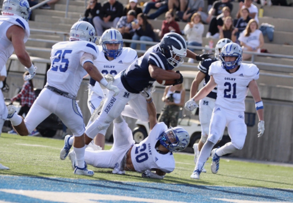 LeeCharles McNeil dives over a defender on his way to score a touchdown during a football game.