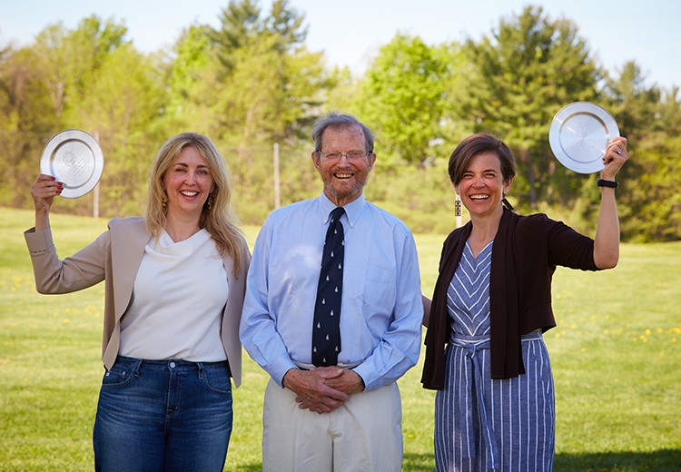 Professors Caitlin Knowles Myers and Sarah Stroup holding up their awards while standing next to Hugh Marlow '57