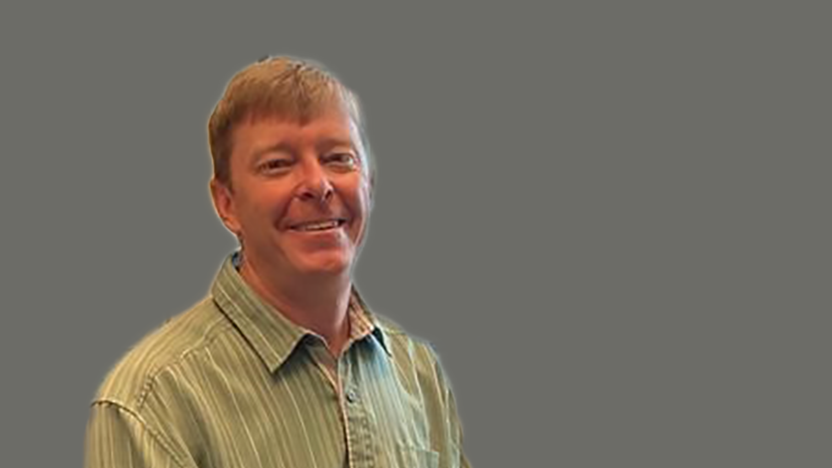 Pete Nelson in short sleeved yellow button-up shirt against grey background