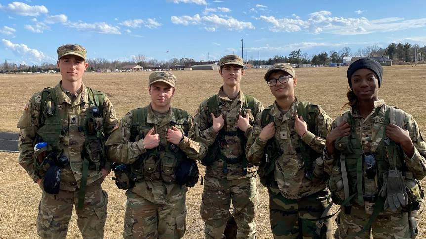 Group of 5 students in their ROTC camo uniforms ready for training. They are looking into the camera