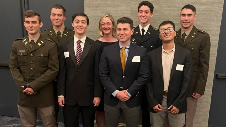 Group of ROTC students in uniform and suit and jacket smiling at the camera.