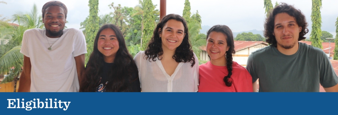 A group of five college-age students of various skin tones, heights, and builds pose in a line on a porch in front of a suburban neighborhood and forest beyond it.Below the picture a blue graphic footer features the word "Eligibility" in white.