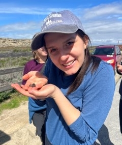 Student wearing a baseball cap smiling and holding a small creature