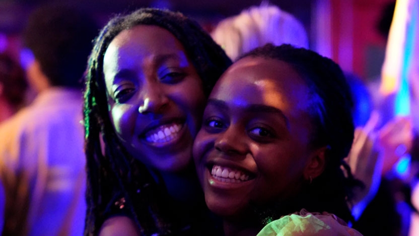 Two women smiling in a night-lit party atmosphere.