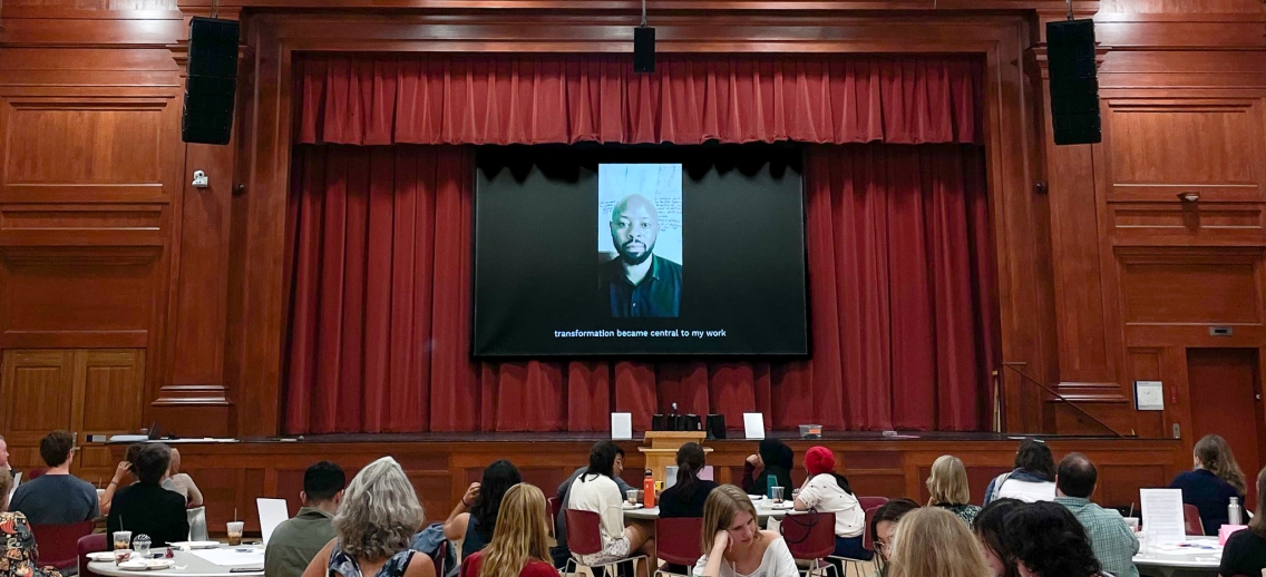 Students watch as Bienfait Mugenza delivers his keynote address virtually.