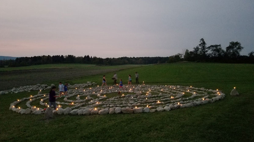 A view of the labyrinth at dusk with candles lighting the pathway.