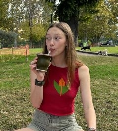 Student in a green park sipping from a mate cup and straw