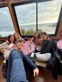 Students taking a selfie in front of windows overlooking the ocean