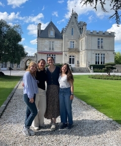 Four students smiling outside of castle-like building