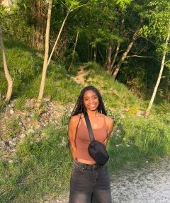 Student posing in front of green grass and trees