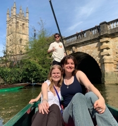 Three students smiling in a boat on a river