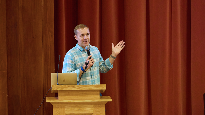 Bill Shufelt gestures at the podium during his talk at Reunion 2025. 