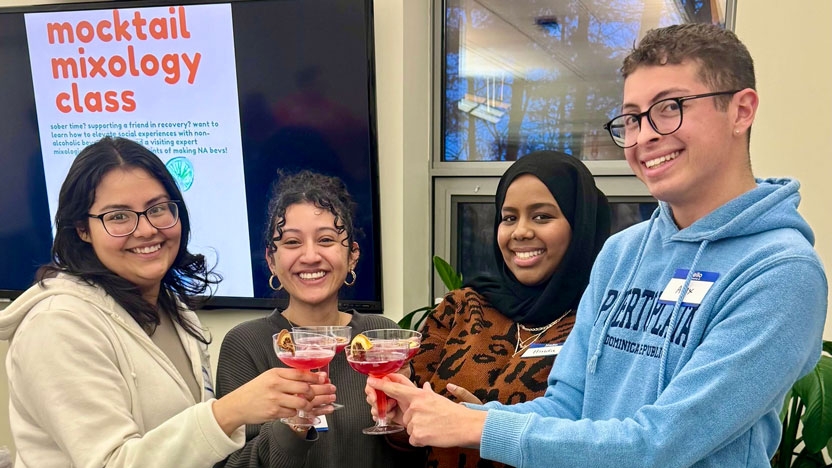 Four students raise their glasses of cranberry colored mocktails.