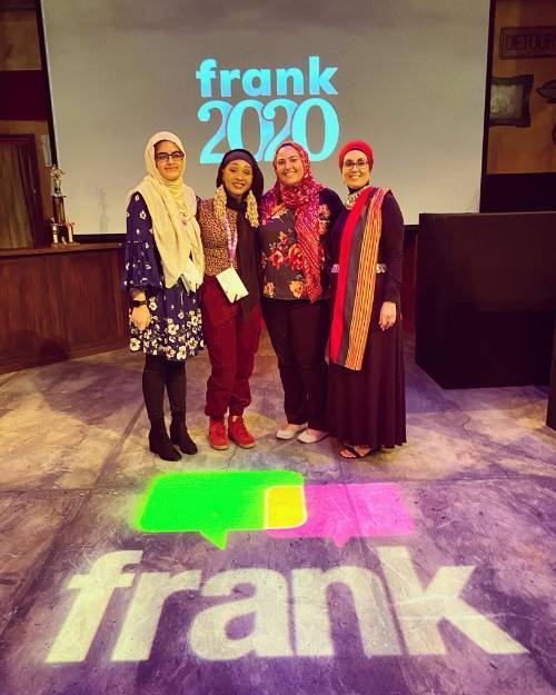 Iftikhar stands with a group of women in front of a projected graphic reading "Frank 2020"