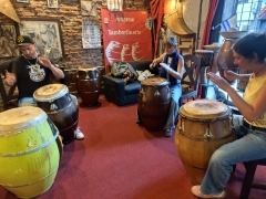 Two students sitting behind large drums with an instructor