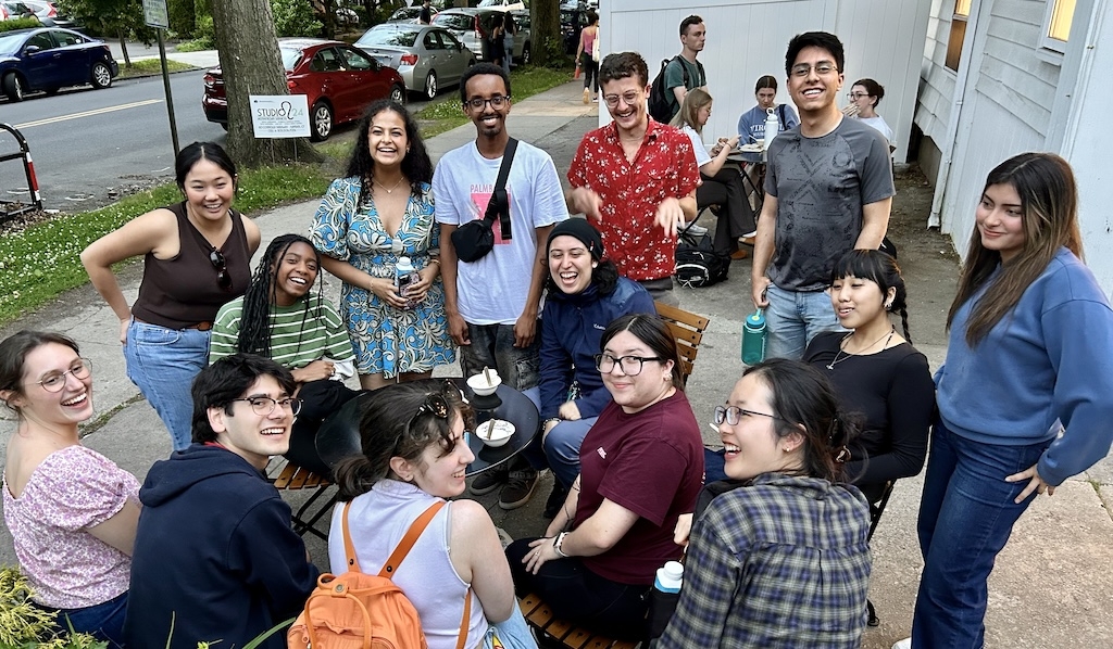 A large group of young people sit and stand smiling at the camera