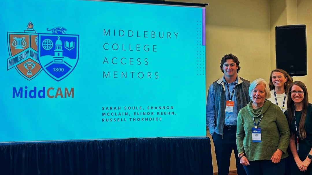 Group of four people stand next to a screen projection that reads Middlebury college Access Mentors