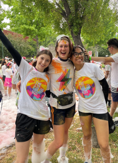 Three students posing at a colorful running race