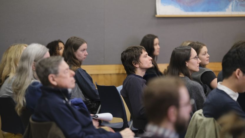 Attentive lecture attendees in a classroom looking to the speakers (our of view) at the front of the room 