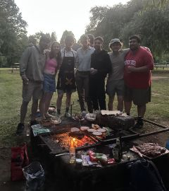 Group of students posing in front of a barbecue fire 