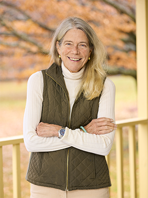 Betsy Sherman Walker in white turtleneck and brown puffy vest with autumn Bread Loaf backdrop