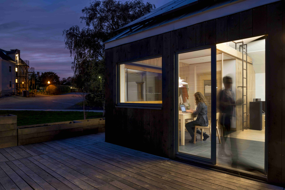 Photo of the outside of Self Reliance House looking in at residents going about their lives with the sunset in the background