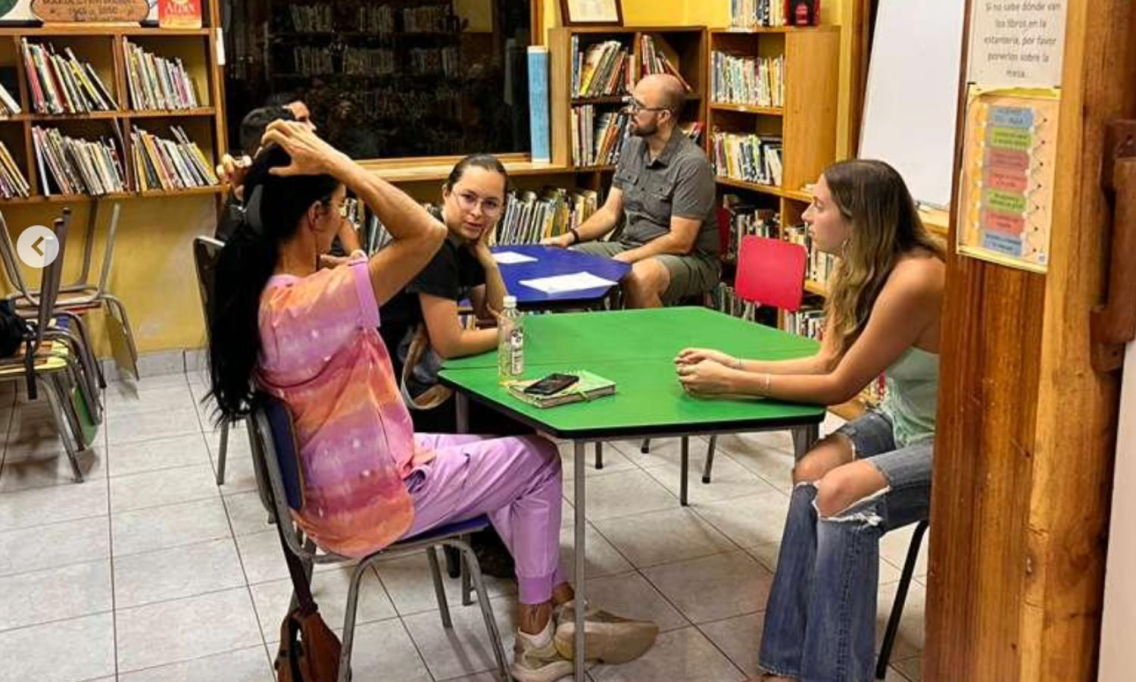 MIddlebury student sits in the community room in the library, speaking to her students.