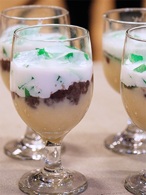 Glasses layered with yellow mung bean, coconut sauce, and green pandan jelly dessert